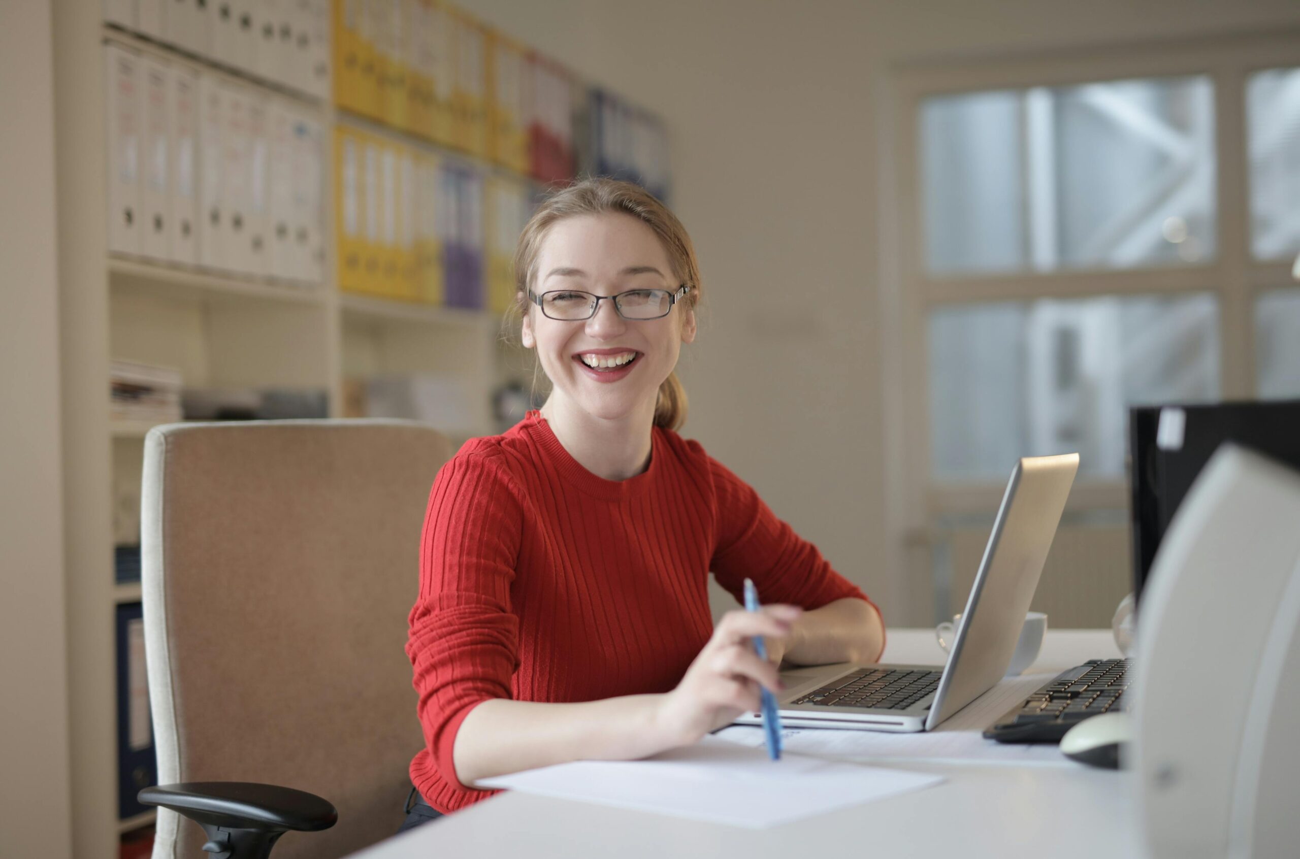 Happy woman smiling at a computer, having started medical board exam preparation with with Dr. Linda Carr.