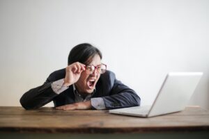 Man in a suit staring in shock at a computer screen.